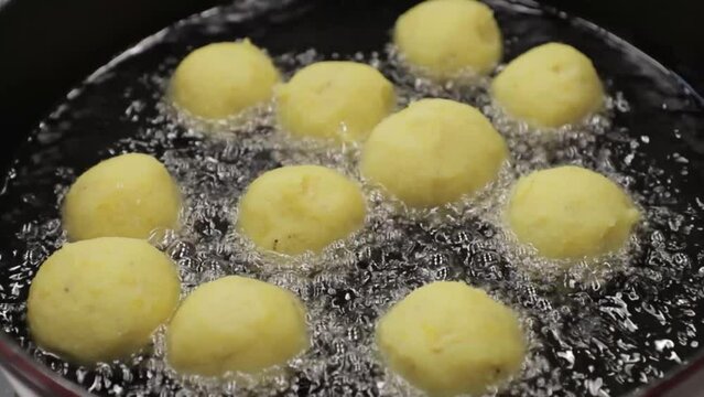 bolas de platano maduro con relleno de queso en un caldero friendose, vista desde arriba, comida dominicana.