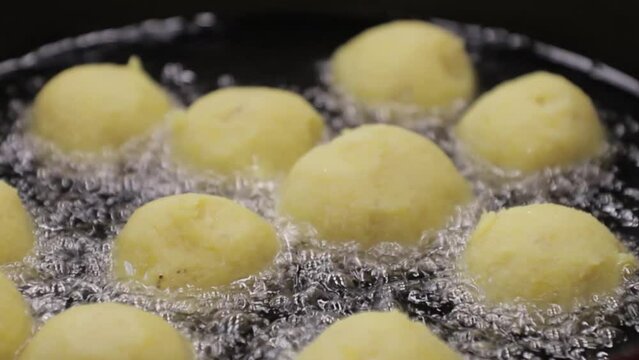 bolas de platano maduro con relleno de queso en un caldero friendose, vista cerrada.
