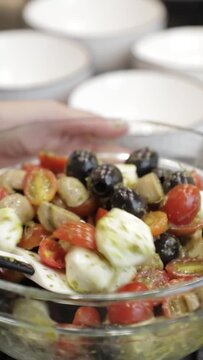 Joven mujer prepara ensaladas en un embase de cristal, Vista Vertical