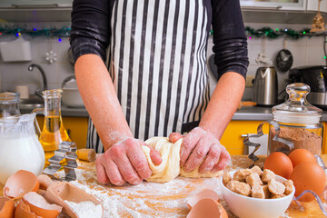 Woman confectioner in a striped culinary apron knead dough for Christmas gingerbread cookies, closeup