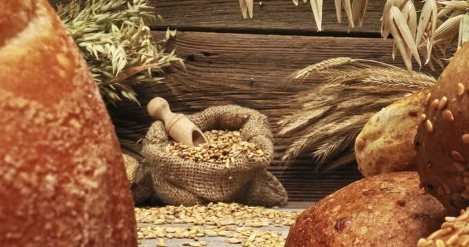 Grains in bag and loaves of bread on wooden table