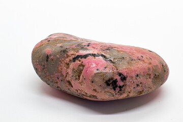 Macro focused tumbled and polished pink rhodonite crystal, manganese inosilicate mineral isolated on a white surface background