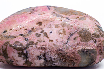 Macro focused tumbled and polished pink rhodonite crystal, manganese inosilicate mineral isolated on a white surface background