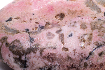 Macro focused tumbled and polished pink rhodonite crystal, manganese inosilicate mineral isolated...