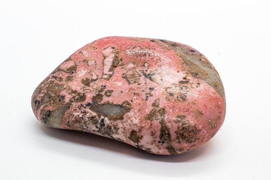 Macro focused tumbled and polished pink rhodonite crystal, manganese inosilicate mineral isolated on a white surface background