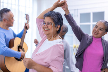 Senior friends on party dancing and playing guitar at home. Elderly musician at party has fun with cheerful family singing together. Leisure activity of Asian Senior.