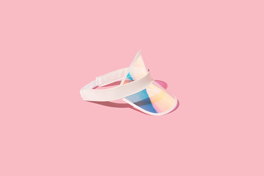 Holographic sports visor hat on sunlight, pink background. Summer vacation relax, sports  accessory, beach hat.