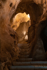vertical photograph of the interior of a cave with winding walls and a staircase.