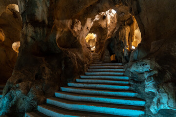 interior of a cave with sinuous walls and artificial stairs leading up to the illuminated bottom