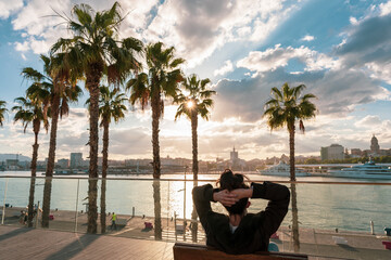 Beautiful shot of a caucasian woman sitting enjoying the sunset in front of a promenade in Malaga. © victor