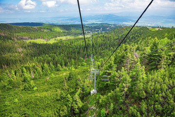 Lift in the mountains. Tourist double lift above the forest on the mountain slope.