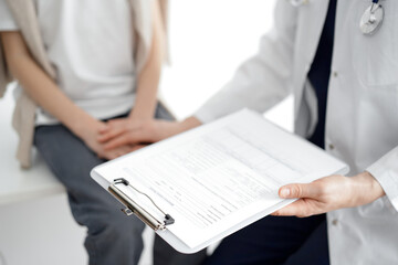 Doctor and child patient. The physician is holding clipboard and reassuring a boy. The concept of ideal health in medicine.