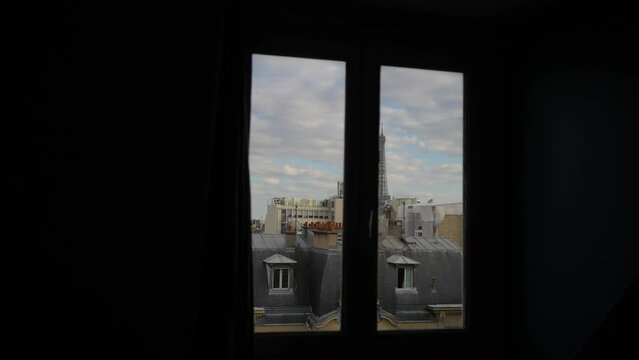 View of Eiffel Tower from apartment window on cloudy day. Tracking shot of peaceful morning view of iconic Eiffel Tower in Paris through open hotel window, slow motion. Travel and romance concept.