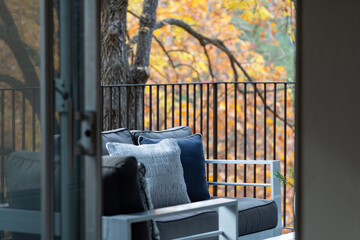 Fototapeta na wymiar Detail view through living room to deck furniture among bright yellow autumn foliage.