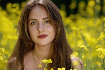 Portrait of a beautiful young woman surrounded by canola flowers.  Clowe-up.