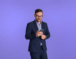 Portrait of young handsome businessman dressed in elegant suit messaging online on smart phone...