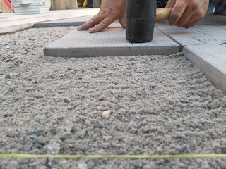 Rubber hammer when laying paving slabs. Laying paving slabs with a kiyanka. A sunny summer day.