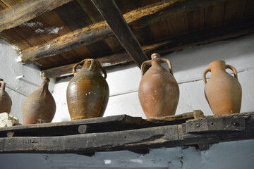 Fototapeta na wymiar A wooden shelf with many clay jugs on it for olive oil