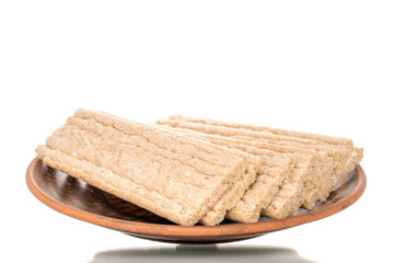 Several rye crispbreads on a clay plate, macro, isolated on white background.