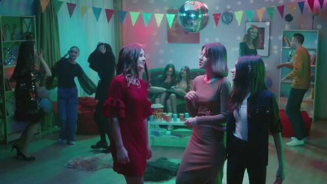 At the party, teenagers dance in separate groups. A group of three girls are dancing separately, the girls are talking, smiling. Dance of three girlfriends close up. Party, birthday, celebration.