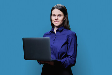 Young business woman posing with laptop, on blue background