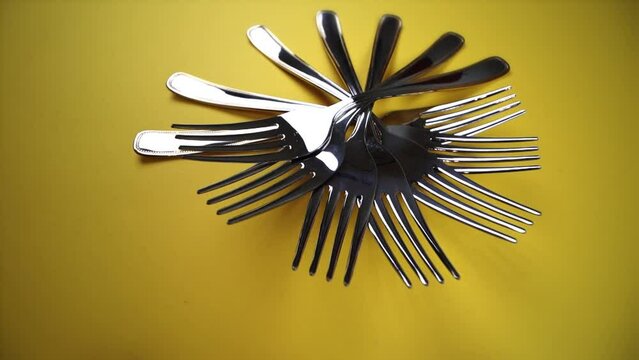 composition with silver forks laid out in circle on yellow