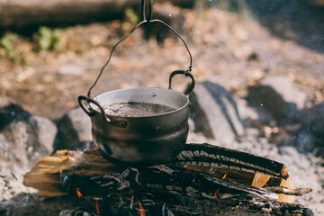 Hiking pot, Bowler in the bonfire. soup boils in cauldron at the stake. Traveling, tourism, picnic...