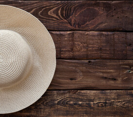 Fototapeta na wymiar half of top view of straw beach hat on wooden background. Space for text