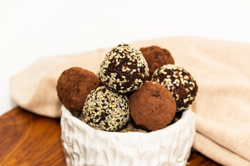 Energy balls in white bowl. Healthy raw dessert, vegetarian truffles, sugar free candies made of dates, hazelnuts, cocoa powder.