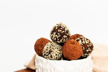 Energy balls in white bowl. Healthy raw dessert, vegetarian truffles, sugar free candies made of dates, hazelnuts, cocoa powder.