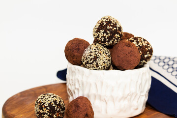 Energy balls in white bowl. Healthy raw dessert, vegetarian truffles, sugar free candies made of dates, hazelnuts, cocoa powder.