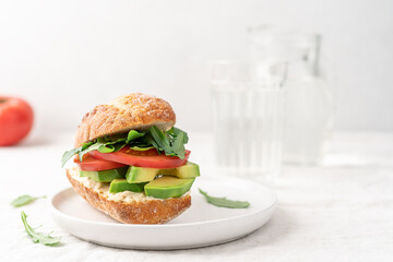 Avocado sandwich with hummus and tomatoes on white background side view with copy space. Healthy snack, fast food