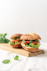 Avocado sandwich with hummus and tomatoes on white background side view with copy space. Healthy snack, fast food