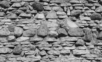 Colorless ruined vintage stone wall. Decolorized black and white wall texture, vintage stone.