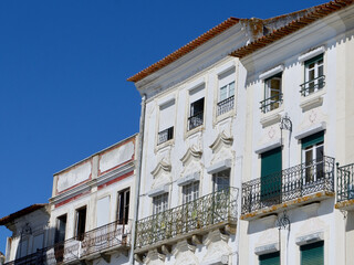 Fototapeta na wymiar Worn bright facades of white colour downtown at Praca do Giraldo square in Evora, Portugal