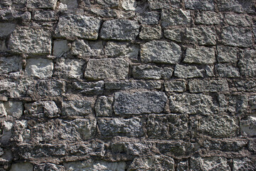 Ancient wall of dark color from destroyed stones. Background, texture of ancient stones, blocks.Ancient wall.