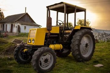 Yellow old tractor on the background of an old house