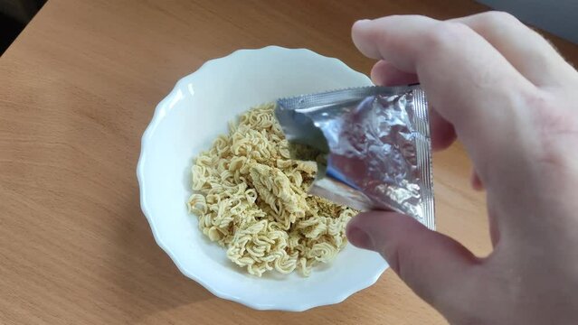Man pouring seasoning into an instant noodles