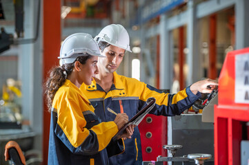 Fototapeta na wymiar two young engineer assistant in helmet inspection check heavy machine construction installation industrial metal roof roll sheet factory. colleague friend worker point finger check operation factory