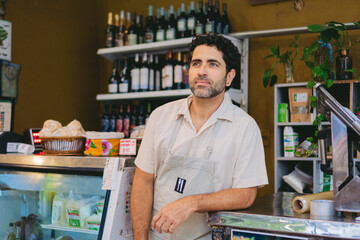 Fototapeta na wymiar latin man owner and seller of an organic grocery store looking at the horizon leaning on a counter