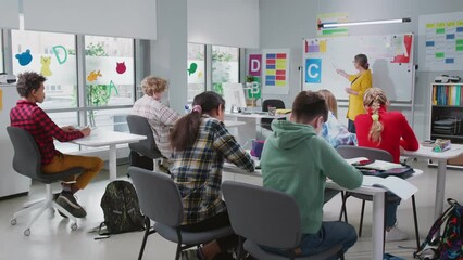 Caring teacher explains lesson to classroom full of diverse children.