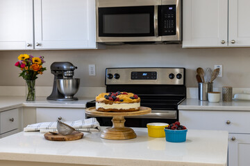 Polish Karpatka Cake on stand on white counter in kitchen setting with berries