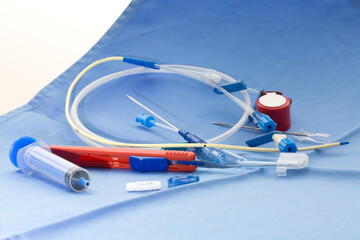 Kit for placement of central venous catheter with red scalpel, blue syringe, guide wire, introducer needle, vessel dilator, and injection caps on blue surgical drape in operation theatre - obrazy, fototapety, plakaty