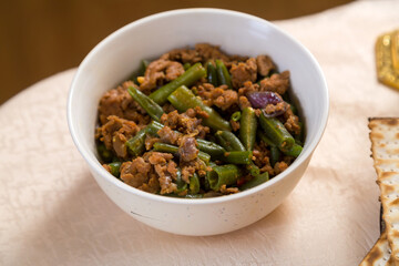 Green beans stewed in spices with meat and garlic on a laid table.
