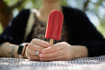 Young girl holding a natural ice cream dessert in hands. Female person holds an organic cranberry ice-cream on stick