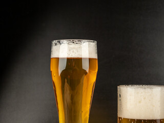 A glass of cold beer on a dark background. Glass of beer close-up.