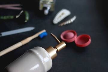 Perfume bottle, hair accessories, soap dispenser and various other beauty products on dark background. Selective focus.