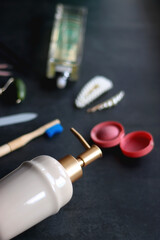 Perfume bottle, hair accessories, soap dispenser and various other beauty products on dark background. Selective focus.