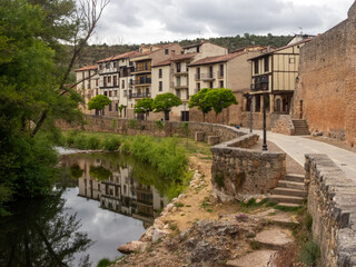 Fototapeta na wymiar Bonito paseo junto al río Arlanza donde se reflejan las casas típicas del pueblo. Covarrubias, Burgos, España.
