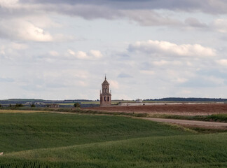 Fototapeta na wymiar Campos de cultivo de cereales y al fondo sobresale la torre de la iglesia de Santa María del Campo. Burgos, Castilla y León, España.